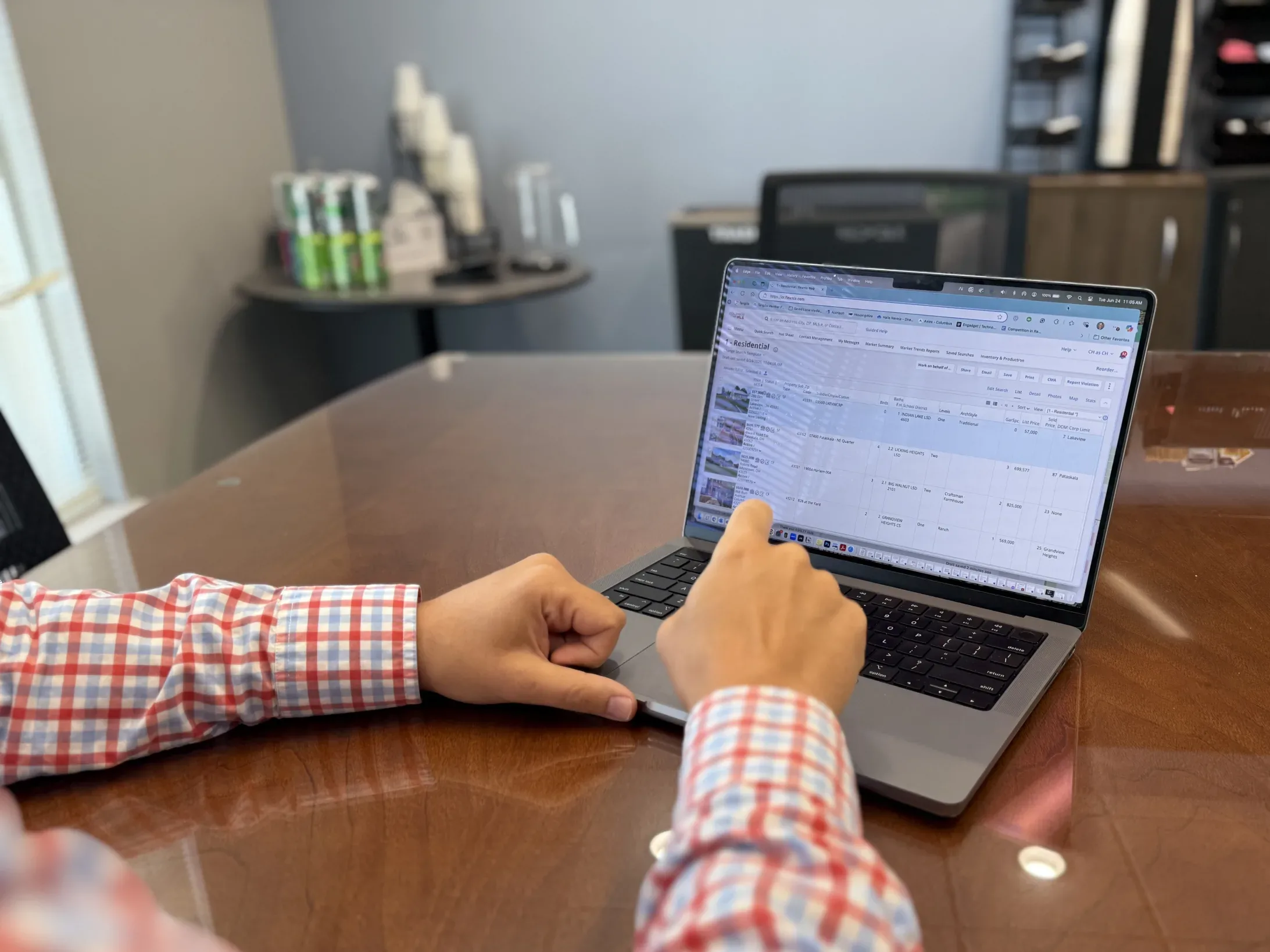 A photo of a hand pointing at real estate listing on a laptop screen.